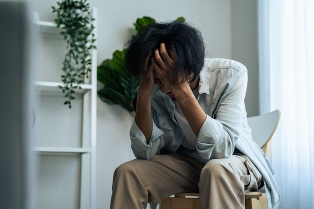 young depressed man sitting alone in living room at home.