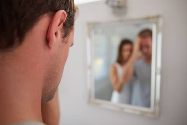 woman supporting man that is sad looking in the mirror.