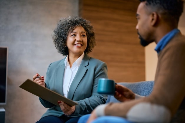 Happy female insurance agent advising African American client during a meeting in the office.
